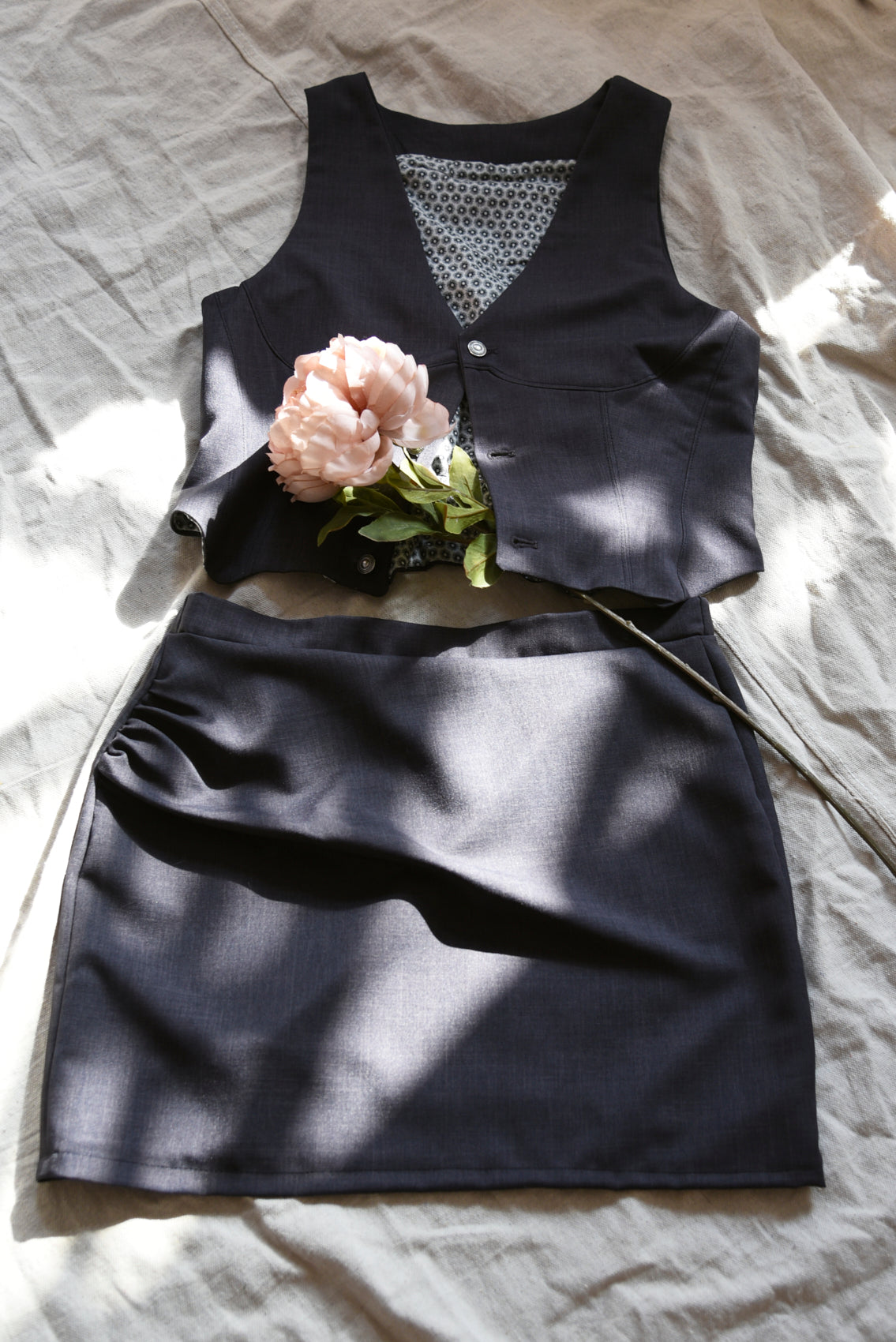 Grey vest and a skirt with a flower on a light fabric background