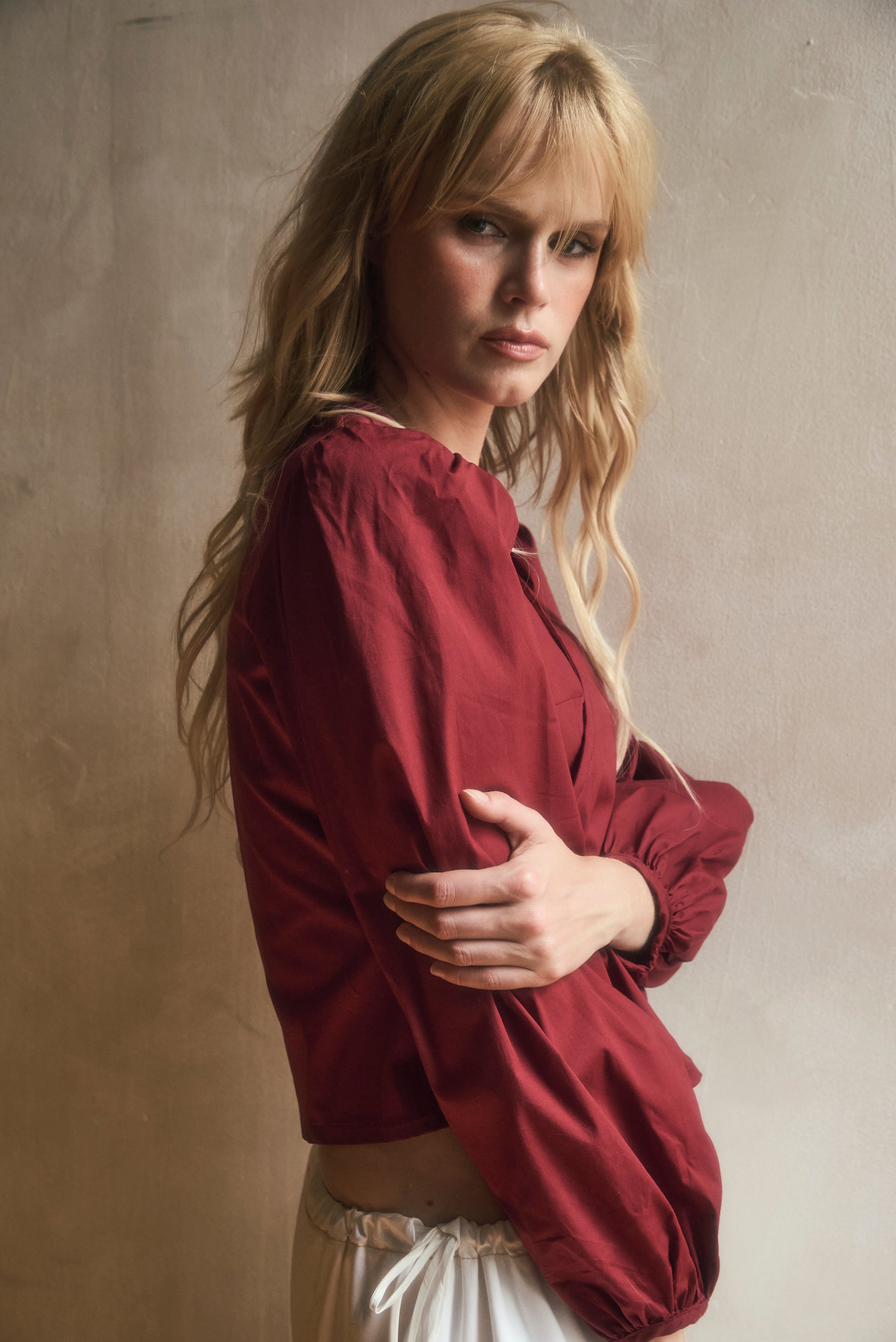 Woman wearing a red burgundy blouse against a neutral background