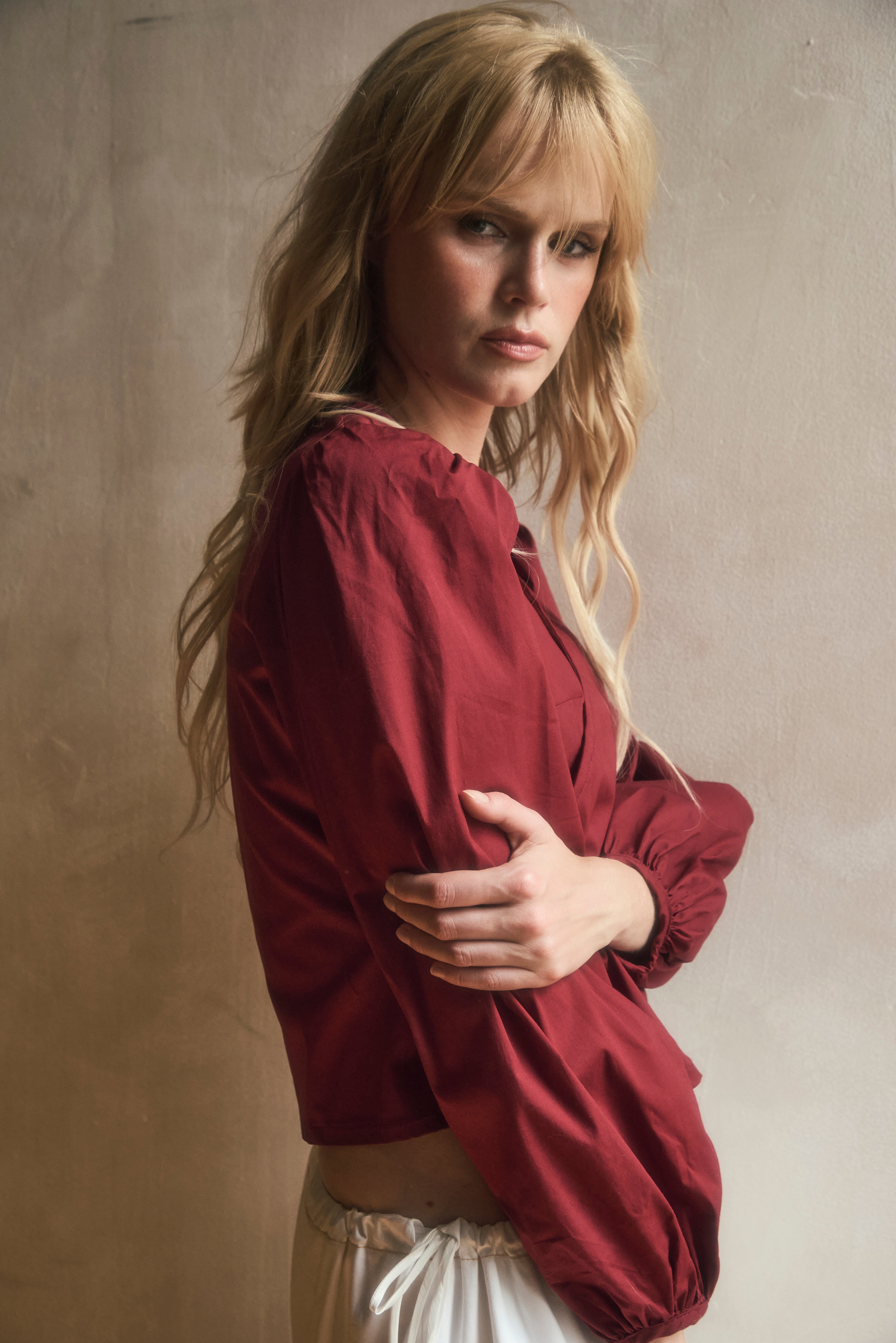 Woman wearing a red burgundy blouse against a neutral background