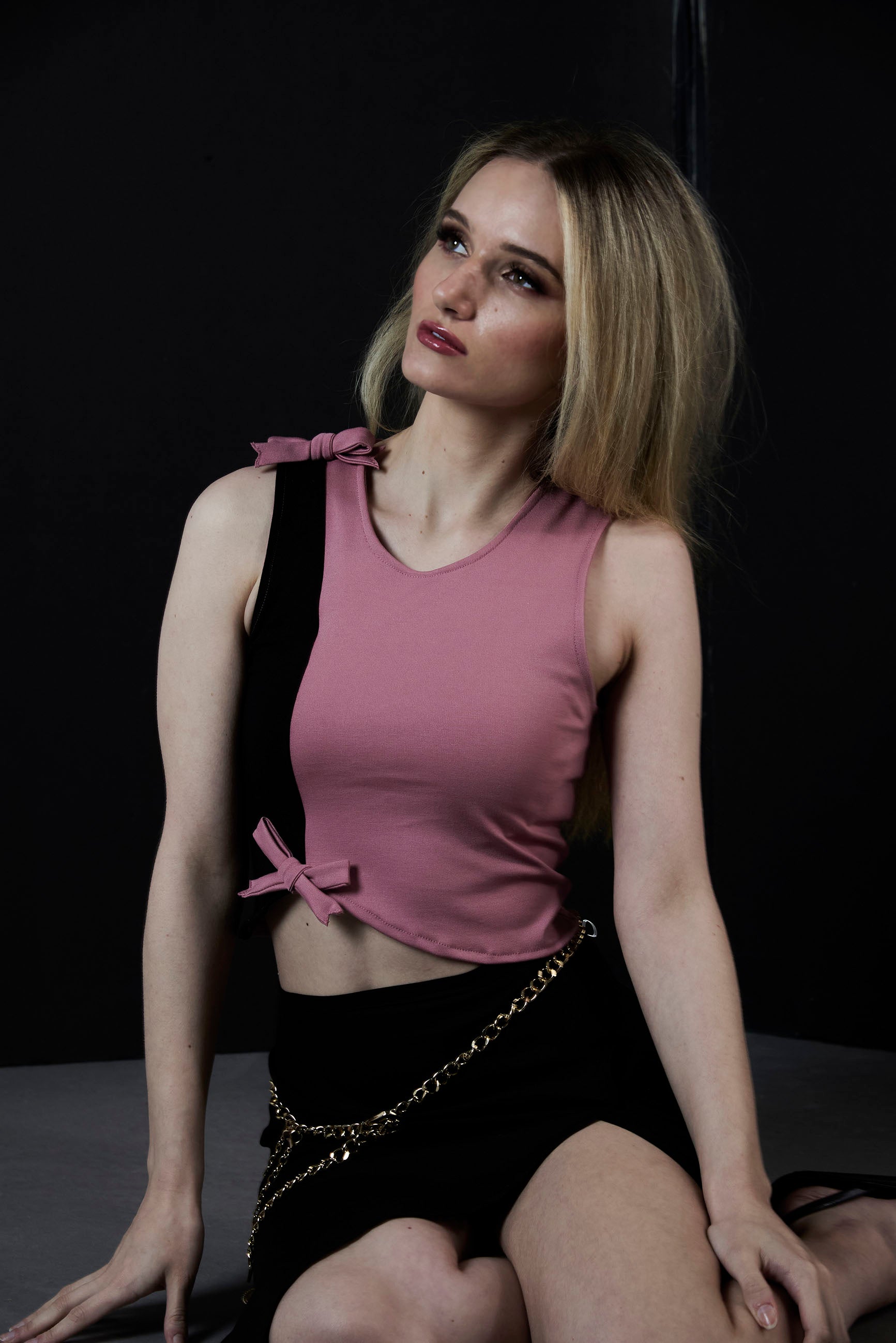 women sitting wearing two tone asymmetrical pink black crop tank top with 2 bows 