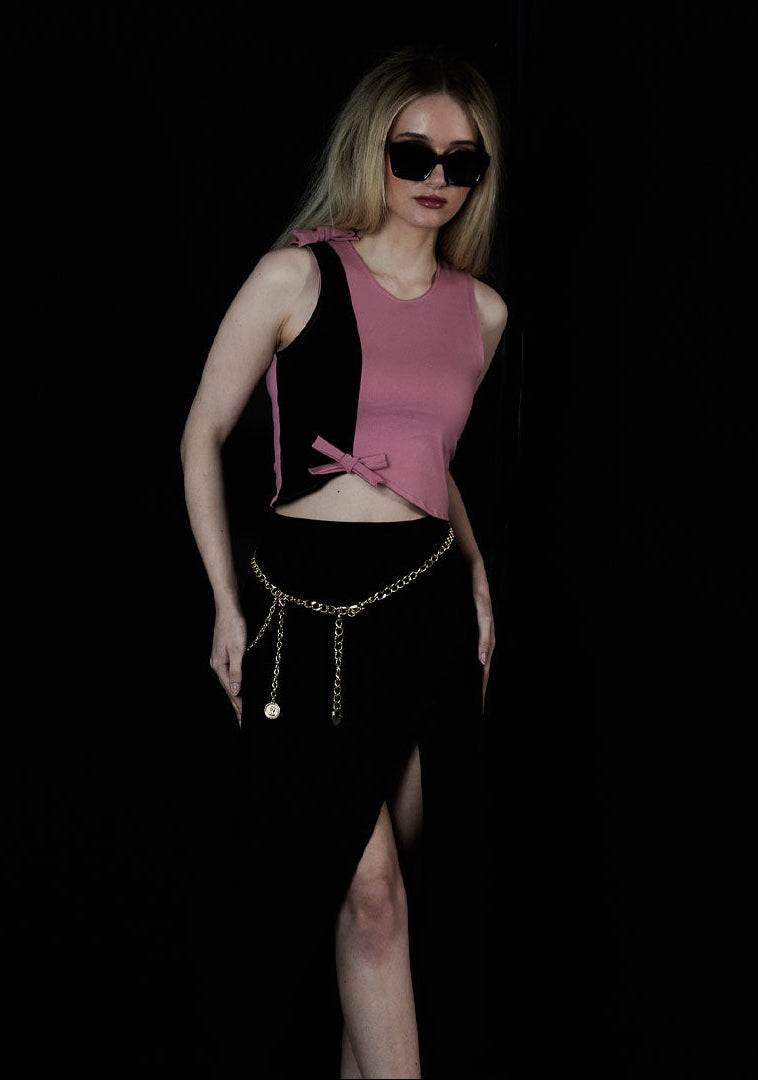 women stending  wearing two tone asymmetrical pink black crop tank top with 2 bows and black skirt with skirt with slit and sunglasses 