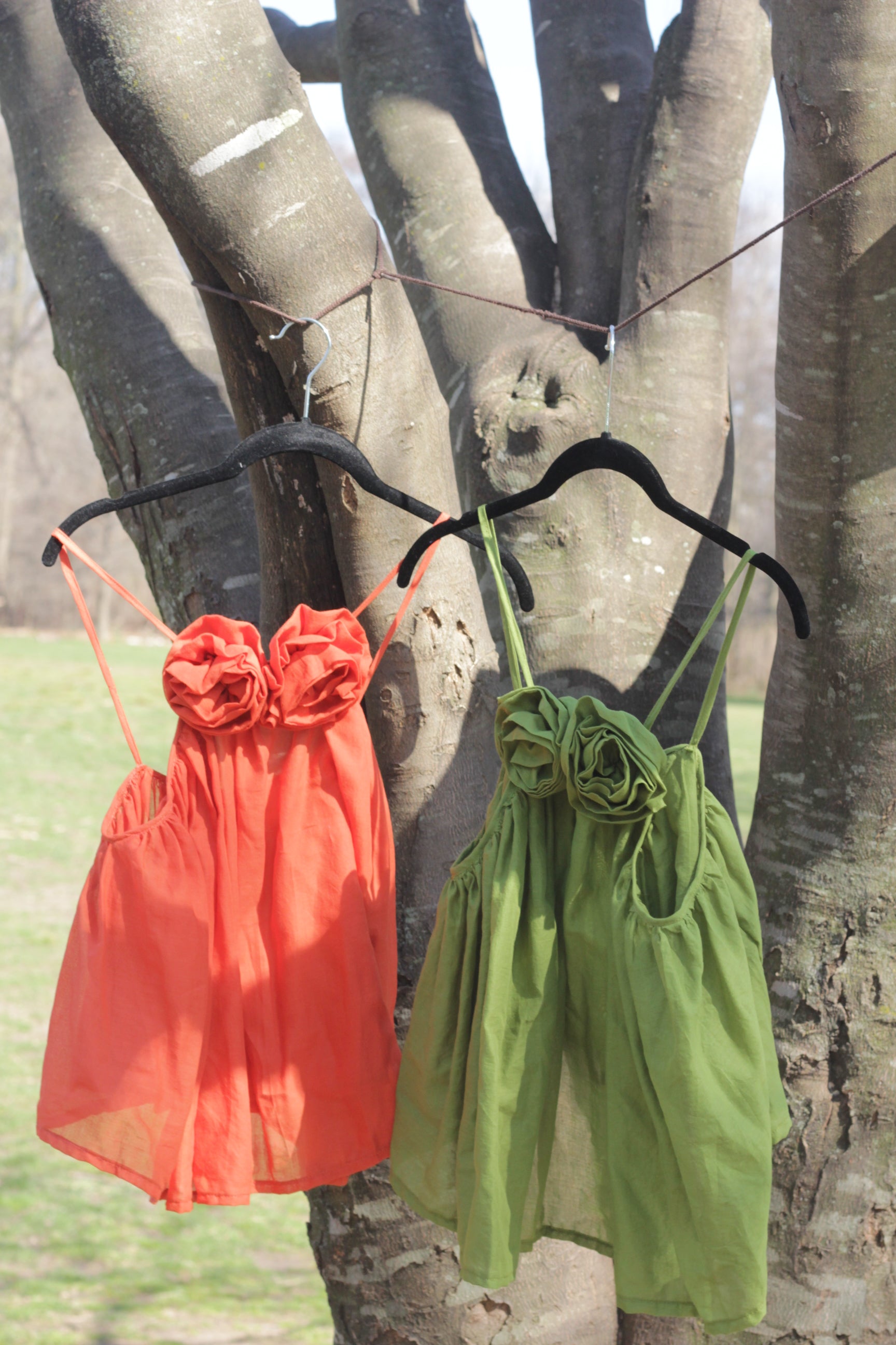 Green and orange tank top hanging on a tree branch
