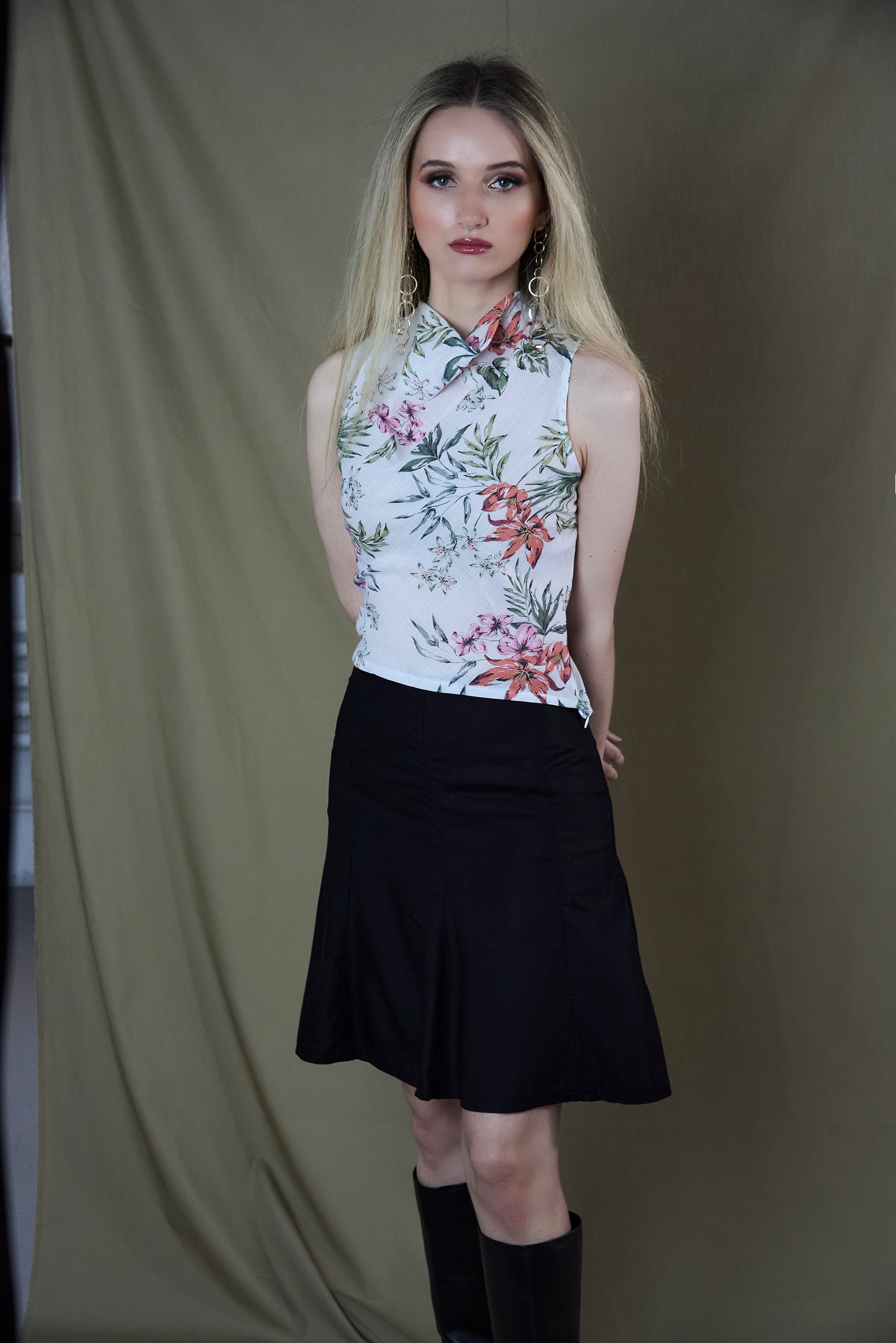 Woman wearing a floral top and black skirt against a plain background