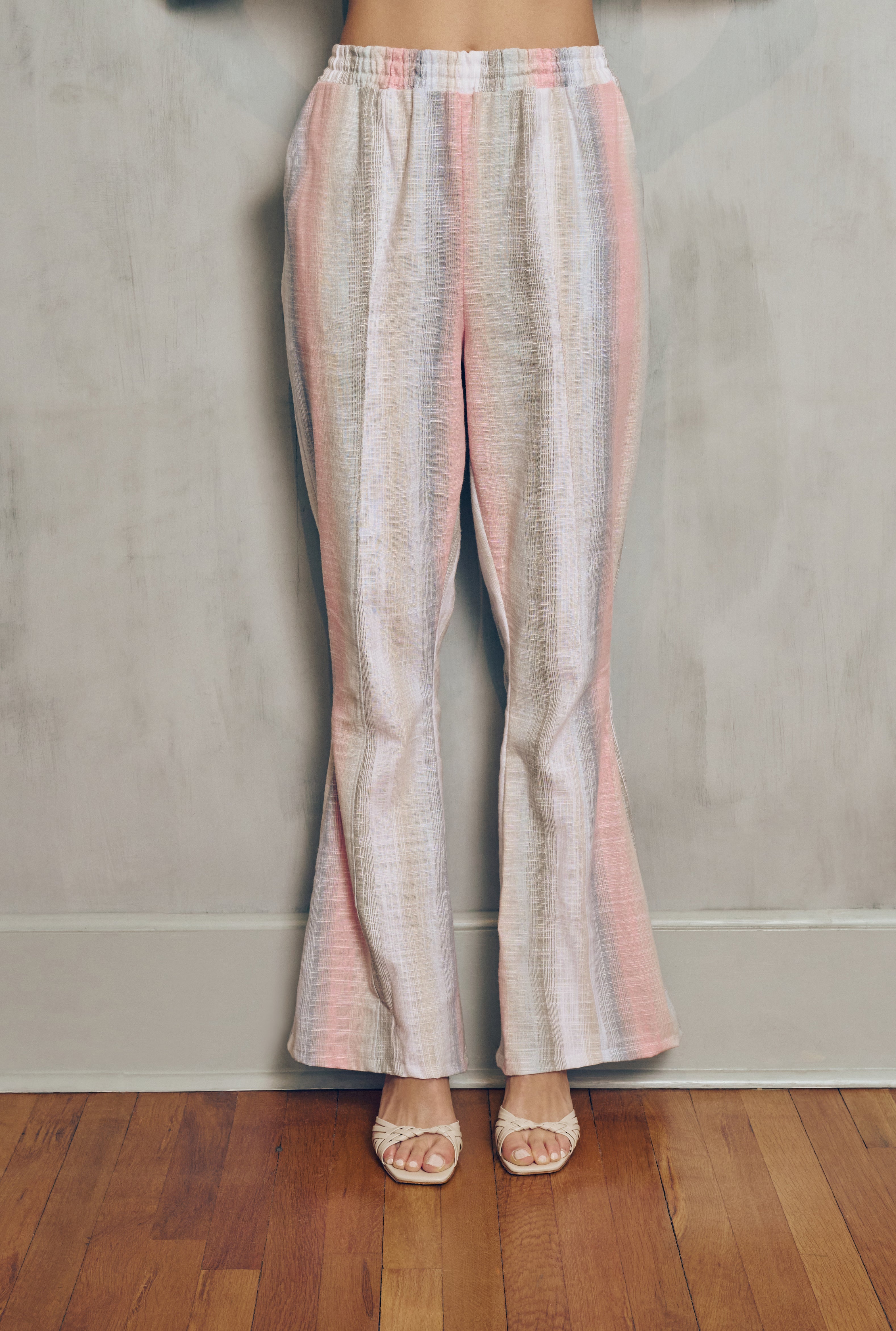 Striped pants worn by a person on a wooden floor with a neutral wall background