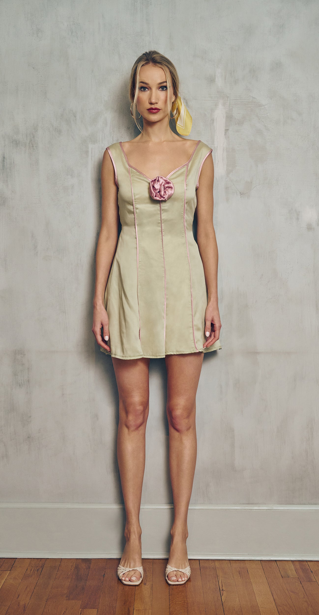 front view Woman wearing a lime green dress with a pink  floral detail against a plain background