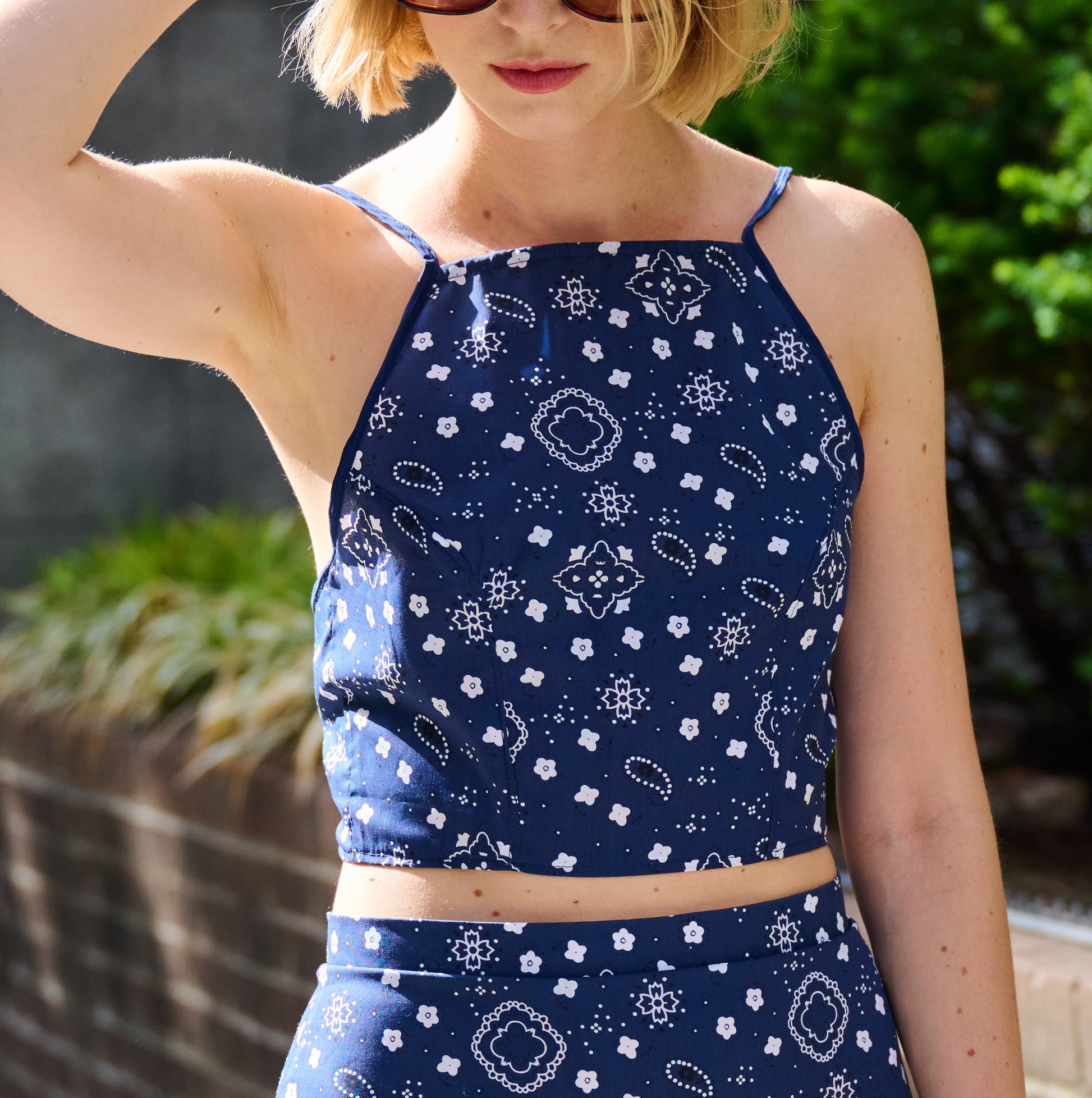 Person wearing a navy blue bandana patterned top and shorts outdoors