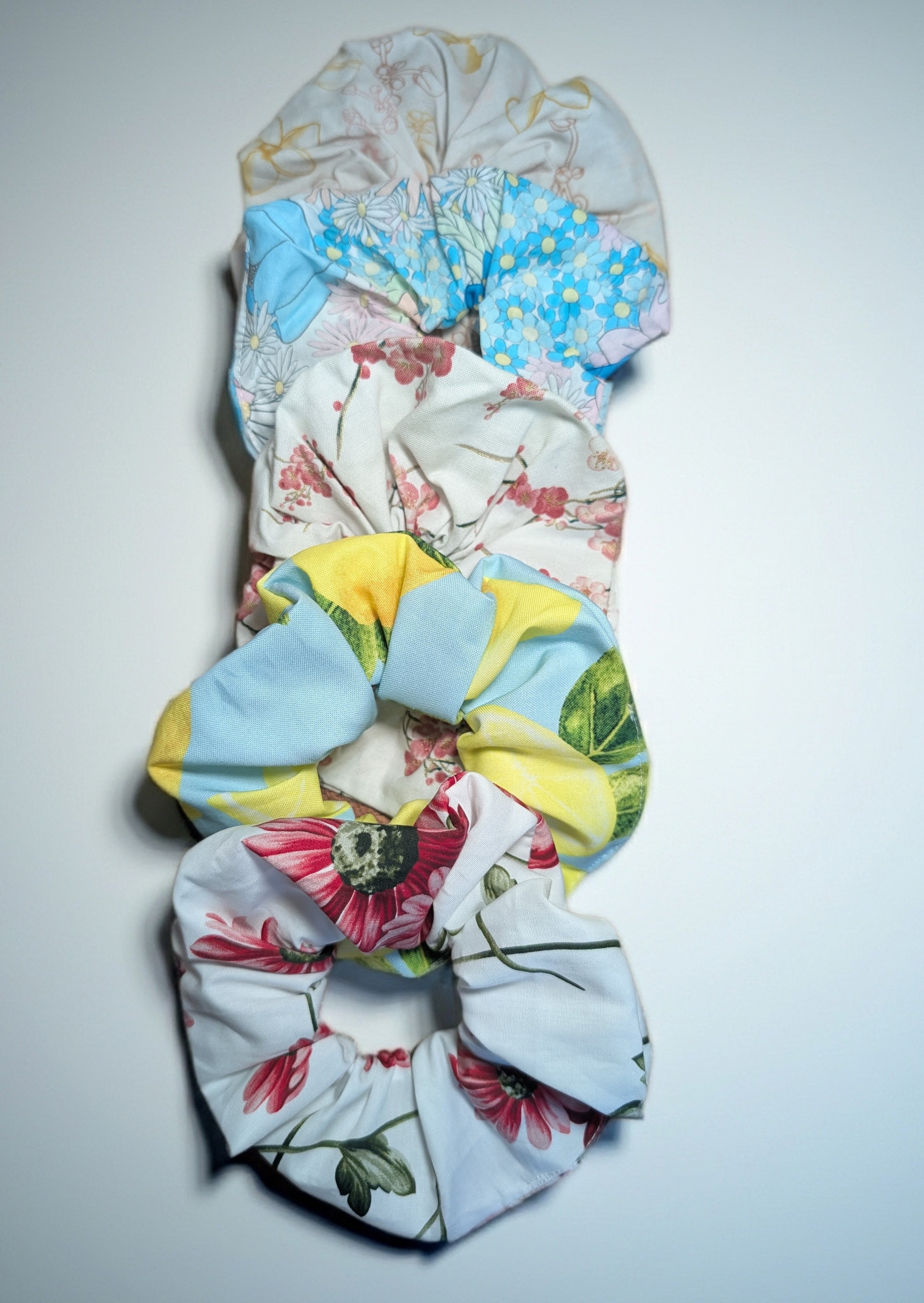 Set of colorful floral scrunchies on a light gray background